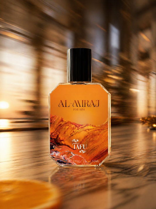 A faceted glass perfume bottle labeled AL-MIRAJ FOR HER by TAFU, filled with amber-orange liquid and featuring a mountain landscape print on the front, set against a blurred warm-toned background.